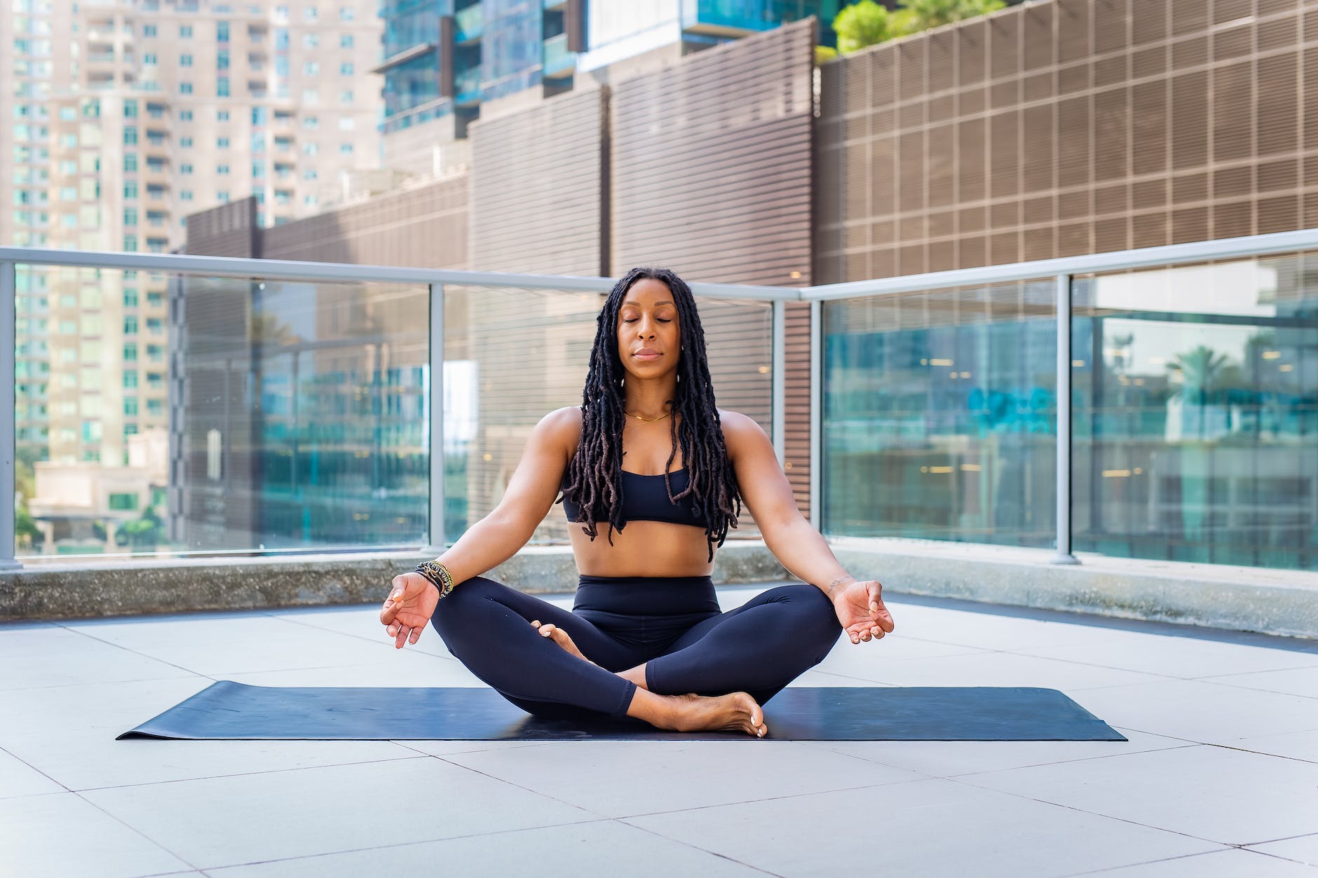 woman meditating on a yoga mat on a balcony